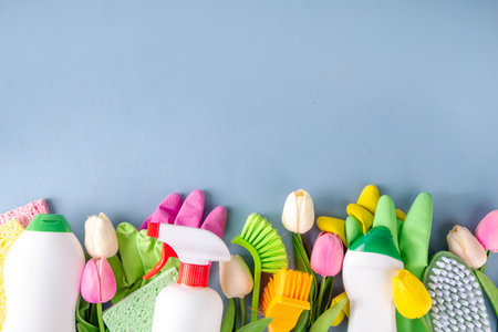 Colorful creative Spring cleaning background, with a bouquet with spring tulip flowers, accessories, cleaning supplies, gloves and brushes on light blue sunny background copy spaceの写真素材