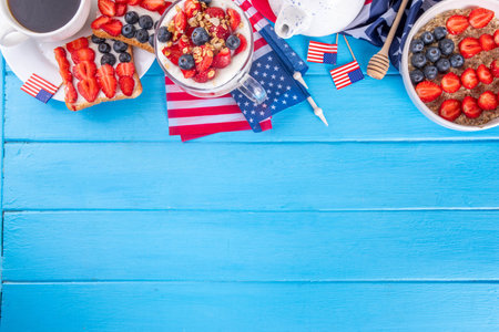 USA patriotic breakfast or brunch with american flag decorated oatmeal, layered yogurt granola dessert, toast sandwiches with fresh berries, and coffee cup on kitchen garden tableの写真素材
