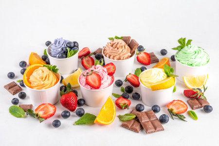 Frozen yogurt assortment. Soft creamy ice cream with chocolate, vanilla, berry, fruit flavors. Various tastes frozen yogurt cup with ingredients - blueberry, chocolate, strawberry, orange, lemon, mintの写真素材