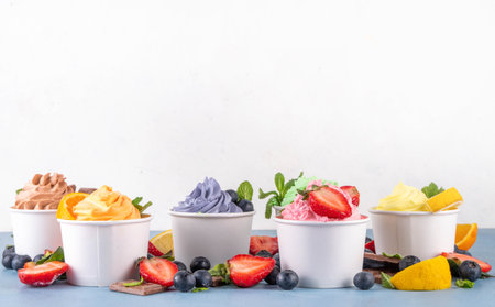 Frozen yogurt assortment. Soft creamy ice cream with chocolate, vanilla, berry, fruit flavors. Various tastes frozen yogurt cup with ingredients - blueberry, chocolate, strawberry, orange, lemon, mintの写真素材