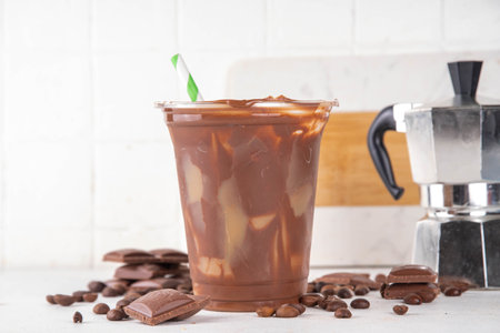 Viral Cracking Chocolate Latte drink. Plastic glass with cracked milk chocolate layer poured with iced latte, sweet coffee moccachino beverageの写真素材