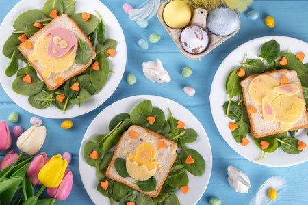 Creative homemade Easter sandwiches for kids breakfast. Funny sandwiches in form of Easter symbols - sheep, chicken, bunny, made with toasted bread, cheese, sausages, spinach and carrotの写真素材