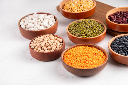 Various dried  beans, lentils, mung, chickpea, pea  assortment in wooden bowls. Legumes on white table top view. Vegan protein sources food, copy spaceの写真素材