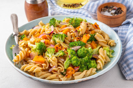 Pumpkin and broccoli vegan warm pasta salad, fall season salad, autumn comfort cozy food conceptの写真素材