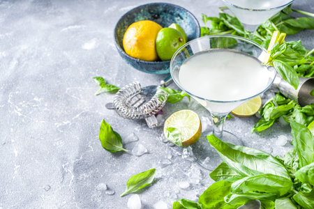 Basil vodka gimlet martini cocktail. Strong alcohol drink with fresh basil, lime and vodka in classic martini glass, Grey stone background copy spaceの写真素材
