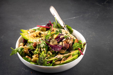 low carb vegan salad various green vegetables, avocado, arugula, spinach, lettuce, with feta cheese, nuts, seeds, peanut butter, avocado and olivesの写真素材
