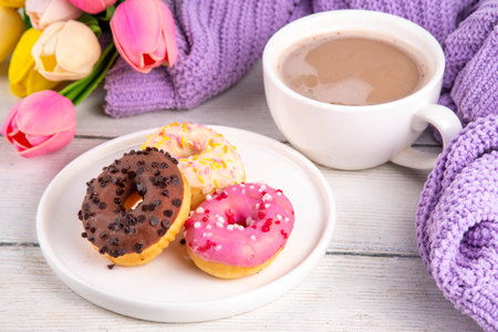 Small sugar glazed donuts with coffee latte cup, tulip flowers, sweater, tulip flower bouquet and note Good Morning. Spring holiday, Mother Day, Woman day, Birthday greeting card backgroundの写真素材