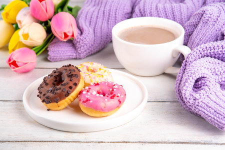 Small sugar glazed donuts with coffee latte cup, tulip flowers, sweater, tulip flower bouquet and note Good Morning. Spring holiday, Mother Day, Woman day, Birthday greeting card backgroundの写真素材