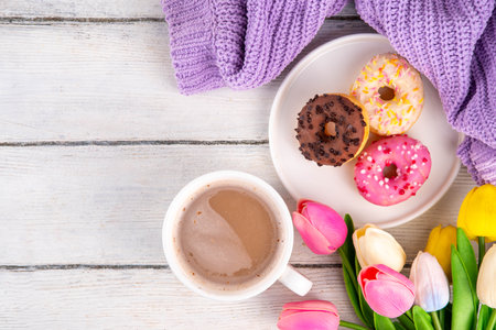 Small sugar glazed donuts with coffee latte cup, tulip flowers, sweater, tulip flower bouquet and note Good Morning. Spring holiday, Mother Day, Woman day, Birthday greeting card backgroundの写真素材