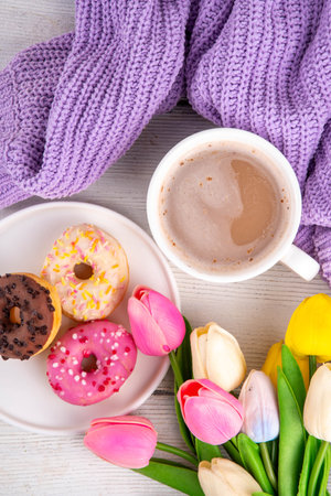 Small sugar glazed donuts with coffee latte cup, tulip flowers, sweater, tulip flower bouquet and note Good Morning. Spring holiday, Mother Day, Woman day, Birthday greeting card backgroundの写真素材