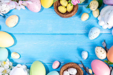 Spring Easter holiday top view flat lay background with eggs, bunny rabbits and spring flowers. Bright colorful greeting card background with copy space.の写真素材