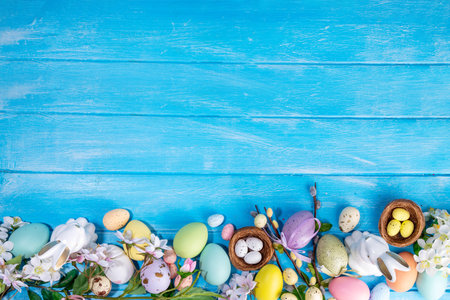 Spring Easter holiday top view flat lay background with eggs, bunny rabbits and spring flowers. Bright colorful greeting card background with copy space.の写真素材