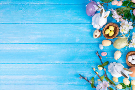 Spring Easter holiday top view flat lay background with eggs, bunny rabbits and spring flowers. Bright colorful greeting card background with copy space.の写真素材