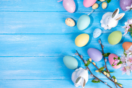 Spring Easter holiday top view flat lay background with eggs, bunny rabbits and spring flowers. Bright colorful greeting card background with copy space.の写真素材
