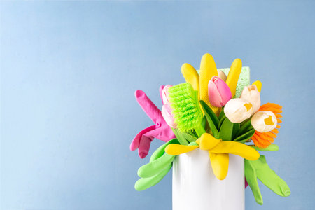Colorful creative Spring cleaning background, with a bouquet with spring tulip flowers, accessories, cleaning supplies, gloves and brushes on light blue sunny background copy spaceの写真素材