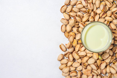 Vegan alternative Pistachio Milk,  Healthy vegetarian drink. Two glass with non-dairy milk beverage, on white kitchen table with pistachio nuts, copy spaceの写真素材