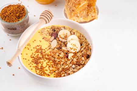 Healthy superfood fruit smoothie bowl with bee pollen, golden creamy shake or smoothie, with granola and banana. Clean eating, dieting vegetarian dish with bee pollen superfood organic powderの写真素材