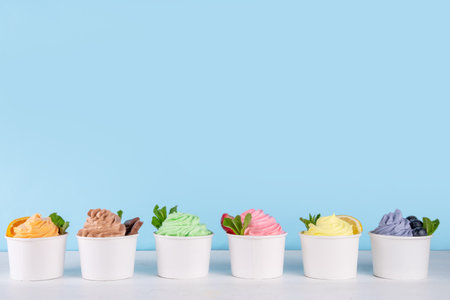 Frozen yogurt assortment. Soft creamy ice cream with chocolate, vanilla, berry, fruit flavors. Various tastes frozen yogurt cup with ingredients - blueberry, chocolate, strawberry, orange, lemon, mintの写真素材
