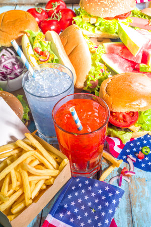 Fourth of July, Memorial Day, USA Independence Day concept. Patriotic, American traditional food. Picnic party with watermelon, burgers, hot dogs, drinks, blue wooden outdoor table backgroundの写真素材