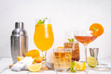 Trendy Tea Inspired cocktail set from green, oolong, black, chai and other tea blends. Sparkling tea soda, cold summer drinks with syrup, lemon, lime and mint, on sun lighted white wooden backgroundの写真素材