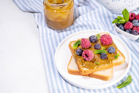 Pistachio paste toast. Summer breakfast delicious sandwiches with pistachio butter spread, with fresh berries. Balanced healthy vitamins and macronutrients snackの写真素材