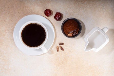 Healthy organic date seed coffee, black coffee cup, made with grated date seeds, with whole date fruits and seeds on beige background . Alternative coffee hot drinkの写真素材