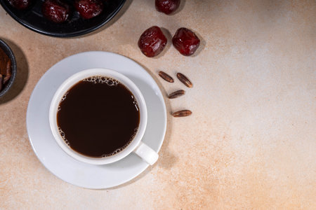 Healthy organic date seed coffee, black coffee cup, made with grated date seeds, with whole date fruits and seeds on beige background . Alternative coffee hot drinkの写真素材