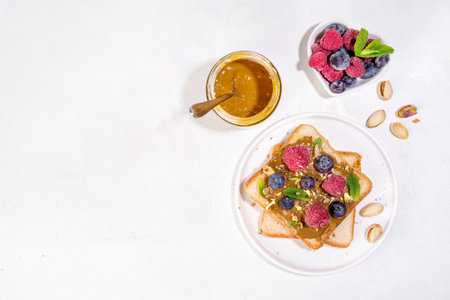 Pistachio paste toast. Summer breakfast delicious sandwiches with pistachio butter spread, with fresh berries. Balanced healthy vitamins and macronutrients snackの写真素材