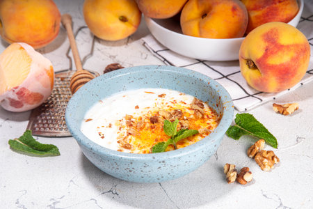 Frozen Shaved Peaches and Cream Dessert, Healthy summer snack with cream or yogurt and shaver frozen peach fruits, with nuts, honey and mint, copy spaceの写真素材