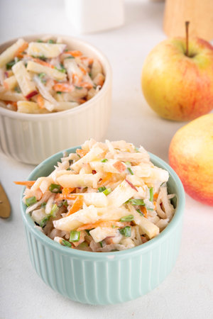 Asian Apple Slaw Salad with Apples, cabbage, carrot and spring onions. Healthy fall vegetable salad with yogurt dressing, in portioned bowls on kitchen tableの写真素材