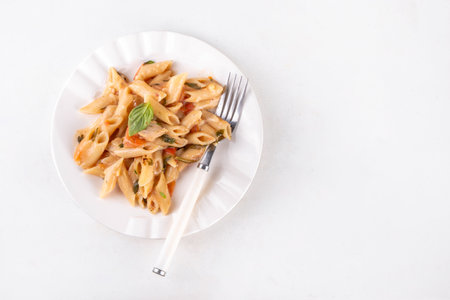 Trendy viral marry me chicken pasta. One pot balanced tender cooked pasta and juicy chicken pieces smothered in creamy and cheesy, garlic sun-dried tomato sauce, wit basil leaves, in plate and potの写真素材