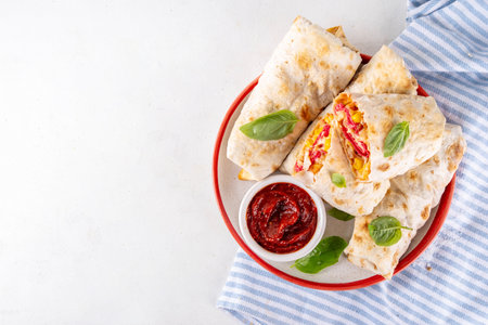 Homemade oven baked Pizza Burritos, pizza style quesadilla wraps with pepperoni or salami, tomatoes, cheese and corn, on kitchen table with hot tomato sauce, copy spaceの写真素材