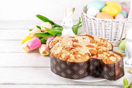 Italian Easter Colomba Cake, Colomba di Pasqua, sweet sugared dove-shaped sponge cake with glazed nuts and fruits, festive fruit- stuffed bread on white Easter holiday decorated table copy spaceの写真素材