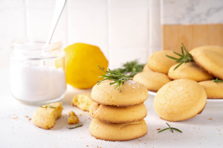 Savory rosemary and lemon shortbread cookies. Salted tasty appetizer crackers with ingredients for cooking on white kitchen tableの写真素材