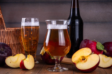 Glasses with Sour Sweet fruit Apple Craft Beer, Cider or Ale on wooden table with fresh red apple slicesの写真素材