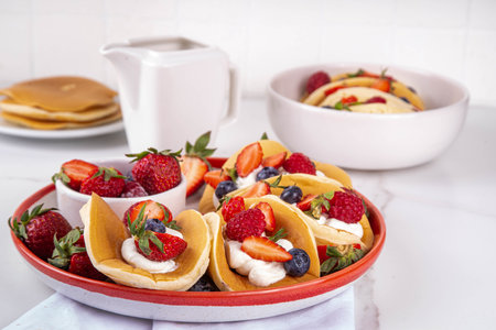 Pancake tacos. Portion of sweet dessert taco made with pancake, whipped cream, cottage cheese or ice cream, fruit and berries. Summer breakfast or brunch recipe, copy spaceの写真素材