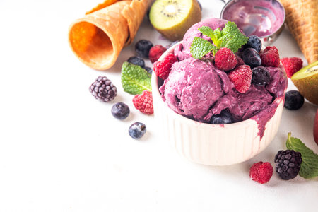 Homemade fruit and berry sorbet ice cream, portioned bowl with healthy fruit and berry yogurt gelato with fresh blueberry, raspberry, strawberry, blackberry, apples, kiwi on kitchen tableの写真素材