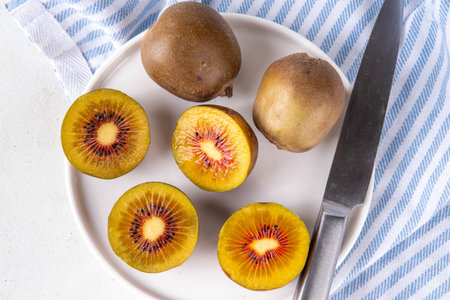 Sweet bright red colored kiwi fruits, whole and sliced, on kitchen table copy spaceの写真素材