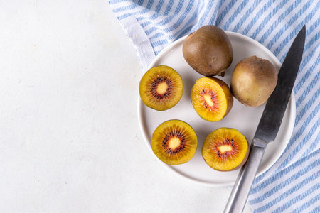 Red kiwi, Sweet bright red colored kiwi fruits, whole and sliced, on kitchen table copy spaceの写真素材