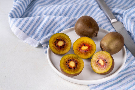Red kiwi, Sweet bright red colored kiwi fruits, whole and sliced, on kitchen table copy spaceの写真素材