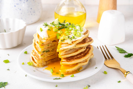 Tasty savory breakfast pancakes with spring green onion and fried eggs. Stack or delicious non-sweet pancakes with scallons, parsley and sunny side up eggs, on white kitchen table copy spaceの写真素材