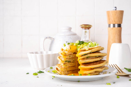 Tasty savory breakfast pancakes with spring green onion and fried eggs. Stack or delicious non-sweet pancakes with scallons, parsley and sunny side up eggs, on white kitchen table copy spaceの写真素材