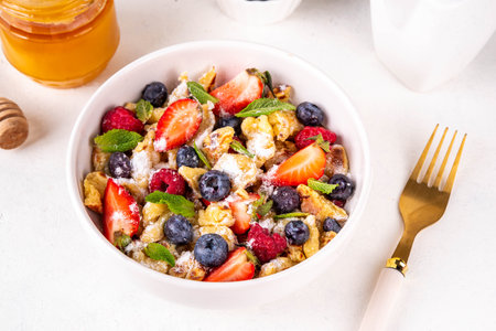 Viral trendy scrambled pancakes with fresh berries, summer sweet breakfast or lunch recipe idea, with powdered sugar and honey, on white kitchen table copy spaceの写真素材