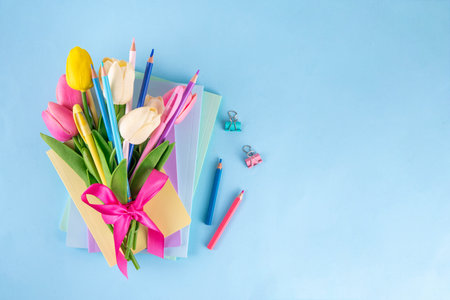 Teacher Appreciation Week background with school supplies and traditional gifts, bouquet of spring flowers with pens, pencils, notebooks, notepads, school bus toy, greeting card to teacher from childの写真素材