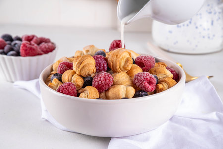 Tiny breakfast croissants cereals with fresh berries and milk. Bowl portions with trendy fresh baked mini petite croissants with raspberry and blueberry, dessert morning snackの写真素材