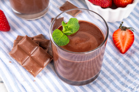 Homemade chocolate pudding dessert, in ceramic portioned bowl on kitchen table, with fresh strawberries, mint and chocolate slicesの写真素材