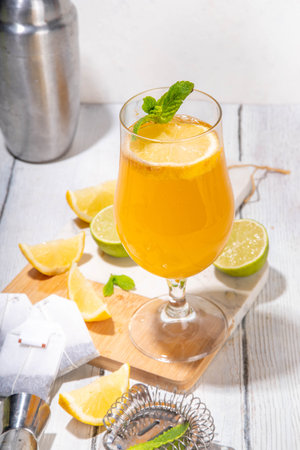 Trendy Tea Inspired cocktail set from green, oolong, black, chai and other tea blends. Sparkling tea soda, cold summer drinks with syrup, lemon, lime and mint, on sun lighted white wooden backgroundの写真素材