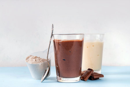 Quick and simple protein pudding. Healthy summer cold dessert. Three glasses with vanilla, chocolate and berry protein pudding, with chocolate slices, fresh strawberry, blueberry, protein powder scoopの写真素材