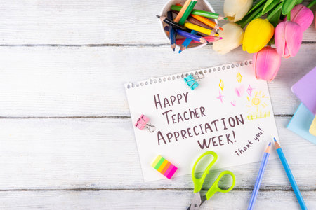 Teacher Appreciation Week background with school supplies and traditional gifts, bouquet of spring flowers with pens, pencils, notebooks, notepads, school bus toy, greeting card to teacher from childの写真素材
