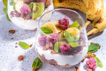 Summer healthy diet breakfast, snack concept. Layered granola breakfast triffle dessert with yogurt and fresh berries  and fruits. Two portioned glass with overnight granola oats parfafait dessertの写真素材